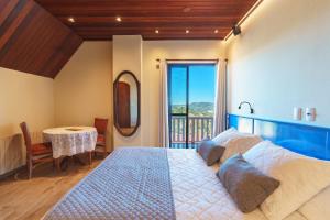 1 dormitorio con 1 cama y balcón con mesa en Pousada Recanto Almeida, en Campos do Jordão