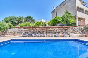 a swimming pool with chairs and a building at Hotel Can Riera in Moscari