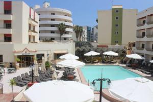 een zwembad met witte parasols en stoelen bij The San Anton Hotel in St Paul's Bay