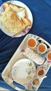two plates of food with toast and two cups of tea at Athalia guesthouse in Rishīkesh