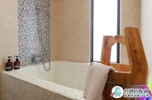 uma casa de banho com uma banheira com um chuveiro e uma janela em 遇見山嵐獨棟包棟民宿寵物友善 em Yuanshan
