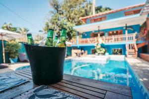 un cubo de botellas de cerveza sentado en una mesa junto a una piscina en Pousada Villa Atlântica, en Camburi