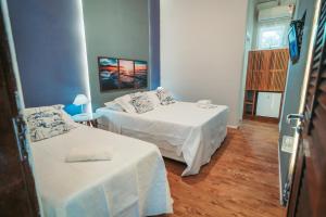 a small room with two beds and a table at Pousada Villa Atlântica in Camburi