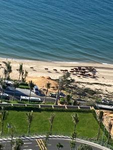 a view of a beach and the ocean with cars at APEC Mandala Cham Bay Mũi Né Condotel - Vietnam in Phan Thiet