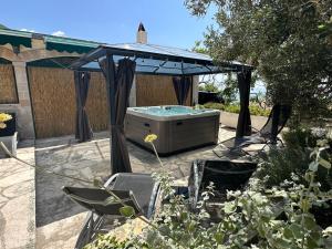 a hot tub under a gazebo in a garden at Jacuzzi apartman Marin in Bol