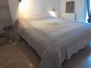een bed met een wit dekbed in een slaapkamer bij Le Mazet de l'Acacia in Beaumes-de-Venise