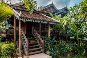 een houten huis met een trap daarheen bij Phum Khmer Lodge - Village Cambodian Lodge in Siem Reap