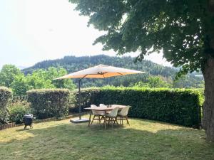 un tavolo e sedie sotto un ombrellone in un cortile di Gîte les Tilleuls ad Arlanc