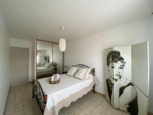Schlafzimmer mit einem Bett mit Bild einer Frau in der Unterkunft Maison Toulouges Climatisée - Proche Perpignan in Toulouges + 14 Fotos