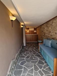 a waiting room with a blue couch and a brick wall at Palorto Traditional Hotel in Gjirokastër