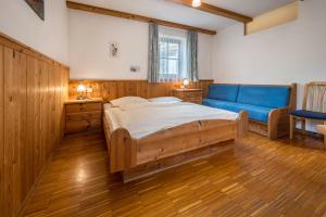 ein Schlafzimmer mit einem großen Bett und einem blauen Sofa in der Unterkunft Lindenhof Apt 7 in Vintl