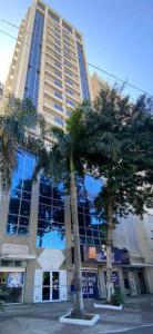 a tall building with palm trees in front of it at Mont Blanc Diamond Flat in Nova Iguaçu