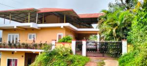 a yellow house with a black fence in front of it at Holidayincoorg Orchid Villa in Madikeri