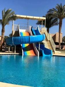 a slide in a swimming pool with a rainbow at Sunset pearl sahl hasheesh in Hurghada