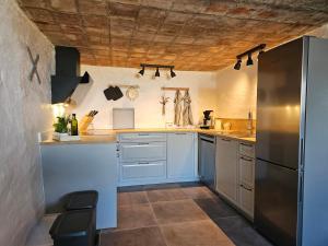 a kitchen with white cabinets and a stainless steel refrigerator at B&B Hygge Jegindø in Thyholm