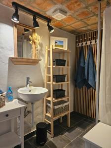 a bathroom with a sink and a shelf at B&B Hygge Jegindø in Thyholm