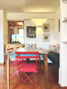 a dining room with a table and two red chairs at Praialonga - Attico con terrazzo in Le Castella