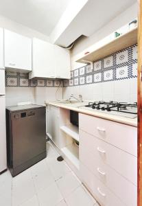 a kitchen with white cabinets and a black refrigerator at Praialonga - Attico con terrazzo in Le Castella