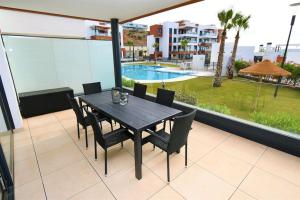 une table et des chaises noires sur un balcon avec piscine dans l'établissement Casa Kerr - Luxury Apt - Sleeps 9 - Los Boliches, à Malaga