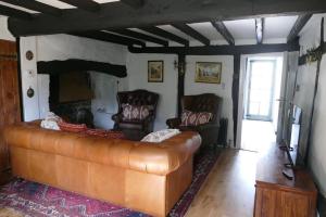 a living room with a leather couch and a fireplace at Hathaway Hamlet in Stratford-upon-Avon