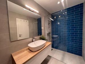 y baño con lavabo, espejo y azulejos azules. en Beachfront Comfort Apartments SINAJKO en Podgora