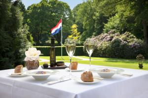 Relais & Chateaux Hotel Landgoed Het Roode Koper في إرميلو: طاولة مع أكواب من النبيذ والطعام عليها