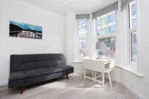 - un salon avec un canapé, un bureau et des fenêtres dans l'établissement The Stafford Apartments, à Bournemouth