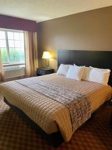 a large bed in a hotel room with a window at The Woodridge Inn in Connersville