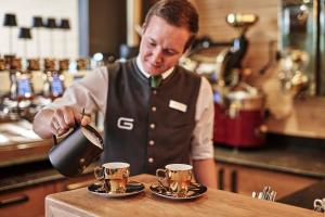 a man is pouring coffee into cups on a counter at Das.Goldberg in Bad Hofgastein