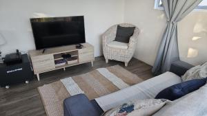 Una sala de estar con un televisor y una silla. en Montrose on Bunkers 2, en East London