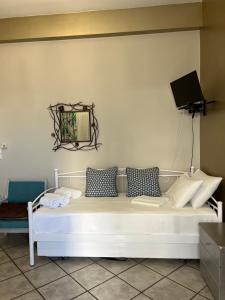białe łóżko z poduszkami i telewizor na ścianie w obiekcie Voula's Apartment w Elafónisos