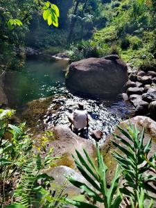 een man op een rots in een rivier bij Hospedaje Bosque del Río in Monteverde Costa Rica