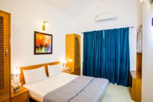 a bedroom with a bed and a blue curtain at 'Golden Sea Breeze' Beach villa in Benaulim