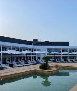 a hotel with a pool and chairs and umbrellas at Silken Platja d'Aro in Platja  d'Aro