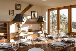 a dining room with a wooden table with chairs and wine glasses at Shockerwick Cottage in Bath