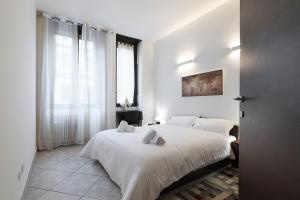 a white bedroom with two beds and a window at PrimoPiano - Casoretto in Milan