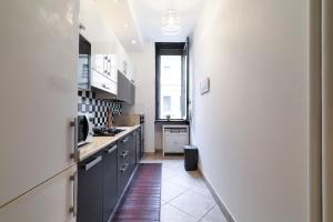 a kitchen with black cabinets and a white wall at PrimoPiano - Casoretto in Milan