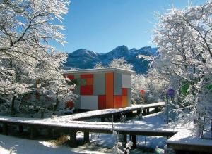 a building covered in snow with trees and mountains at Cabañas Ecobox Andino in Las Trancas