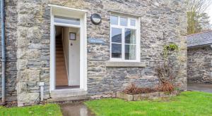 a stone house with a white door and a window at Forge Cottage in Rusland