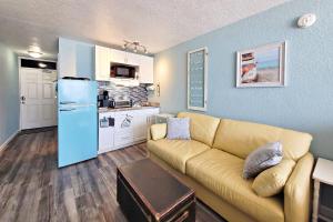 Pirates Cove Condo Unit 406 في Daytona Beach Shores: غرفة معيشة مع أريكة ومطبخ