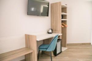 een bureau met een blauwe stoel en een tv aan de muur bij HOTEL NARCEA in Santa Pola