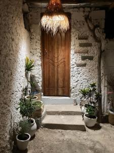 a wooden door in a stone building with potted plants at Malaika House Paje in Paje