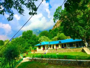 Chitral Inn Resort (Kalash Valley) في شيترال: منزل بسقف ازرق في ميدان