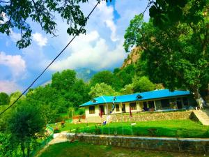 a house with a blue roof in a field at Chitral Inn Resort (Kalash Valley) in Chitral