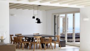 a dining room with a black table and chairs at Home of the Gecko - Mykonos Town in Megali Ammos