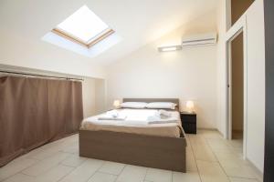 a white bedroom with a bed and a skylight at Royal Playa Suite and Apartament -private parking- self chek out in Catania
