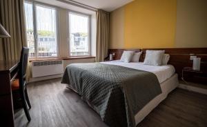 a hotel room with a large bed and two windows at LOGIS HOTEL - La Petite Rade in Le Havre
