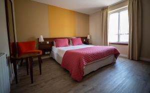 a bedroom with a bed and a chair and a window at LOGIS HOTEL - La Petite Rade in Le Havre