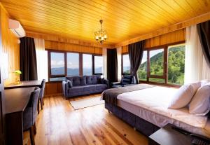 a bedroom with a bed and a desk and windows at Avulot Mountain Resort Hotel in Trabzon