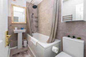 a bathroom with a tub and a toilet and a sink at Spacious & Welcoming 4BD House - Kennington in London